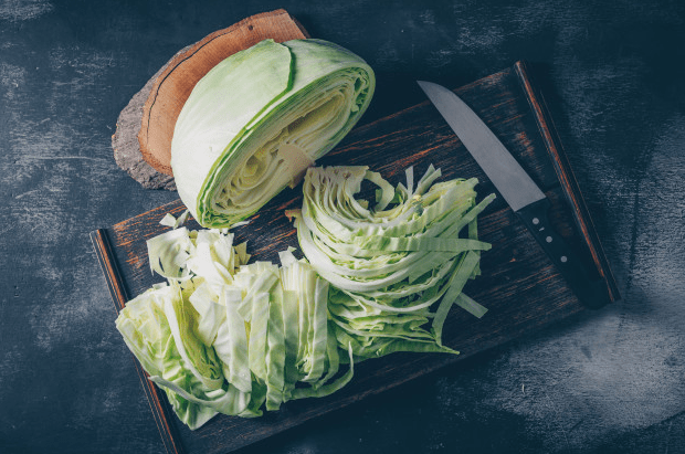Freshly chopped green cabbage on a cutting board with a knife.