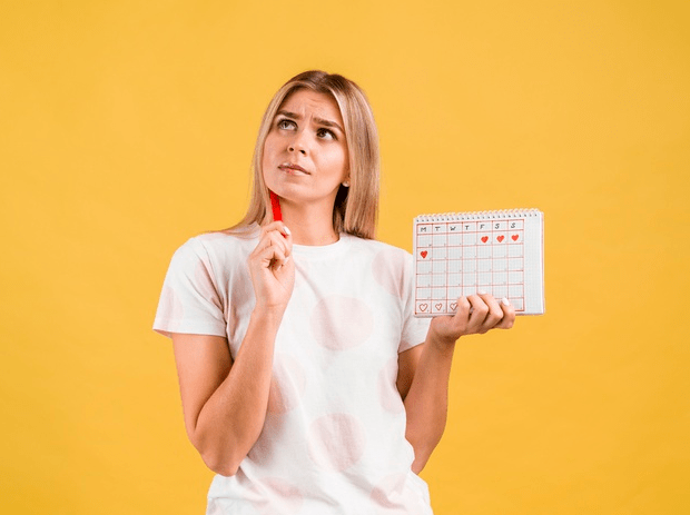 Medium shot of woman thinking and holding the period calendar.