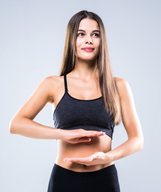 the woman with hand gestures heart shape on the belly