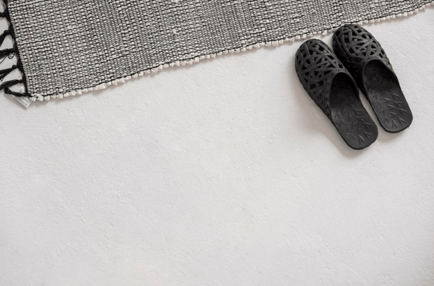 Slippers on the floor near carpet.