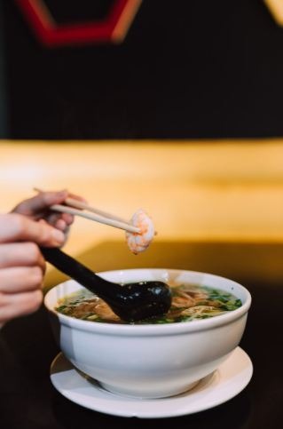 A person having a bowl full of soup noodles