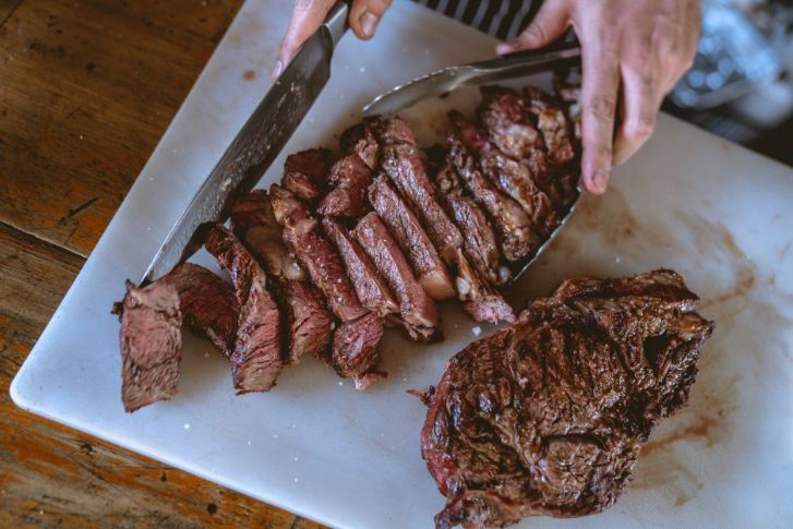 A person slicing cooked meat.