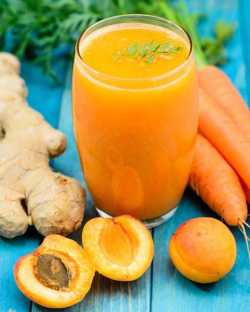 Glass of apricot carrot juice on blue wooden  table
