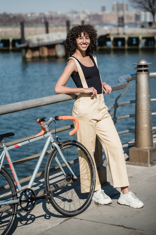 A cheerful woman with dark curly hair near a bicycle on an embankment