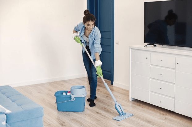 Housewife working at home. Lady in a blue shirt. woman clean floor