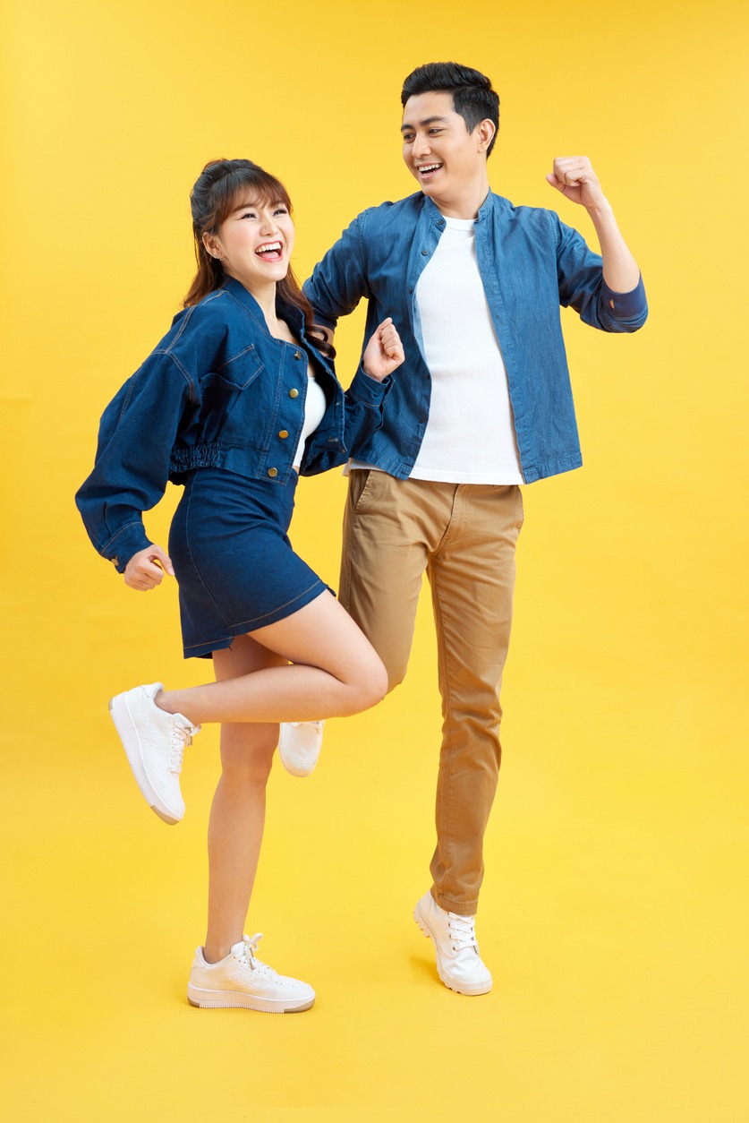 Full length body size photo funky she her he him his pair jumping high raised fists yell scream shout loud wear casual jeans denim white t-shirts isolated yellow background
