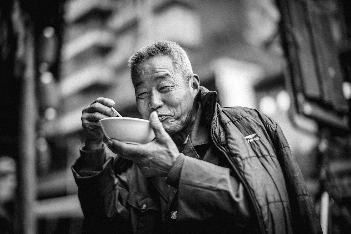 Old man eating on a bowl