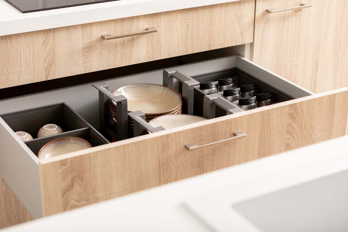 Organized kitchen drawers with plates, spices and cups in drawer organizers